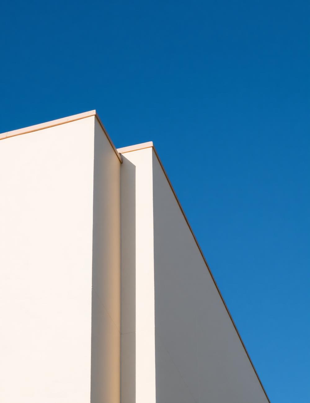 Off-white stucco parapet and reveal joint against a deep blue sky